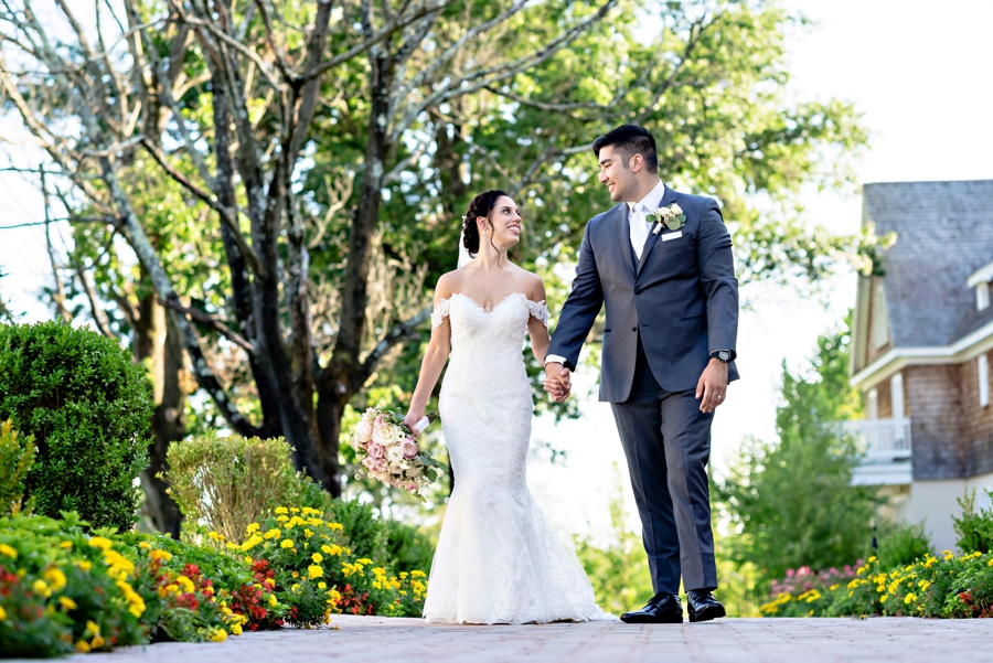 A groom and bride walk along a path filled with flowers at their wedding at the ryland inn in nj.